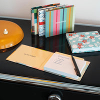 Colorful notebooks and a pen on a black surface with a vinyl record in the background.