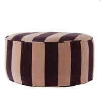 A striped pouf in blush and maroon colors with a black leather handle.