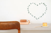 art work in shape of heart made from paper leaves on white wall