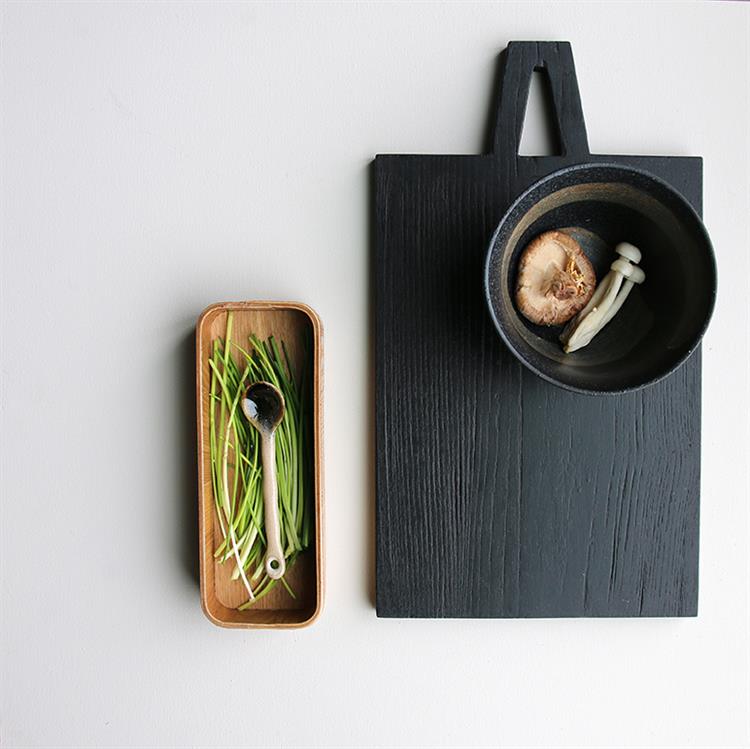 stylish black cutting board and ceramic teaspoon in tray