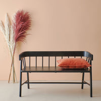 black wooden bench in shaker style in front of a peach colored wall