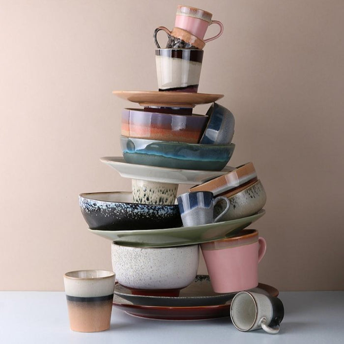 artsy stack of pastel colored ceramic plates, bowls and mugs