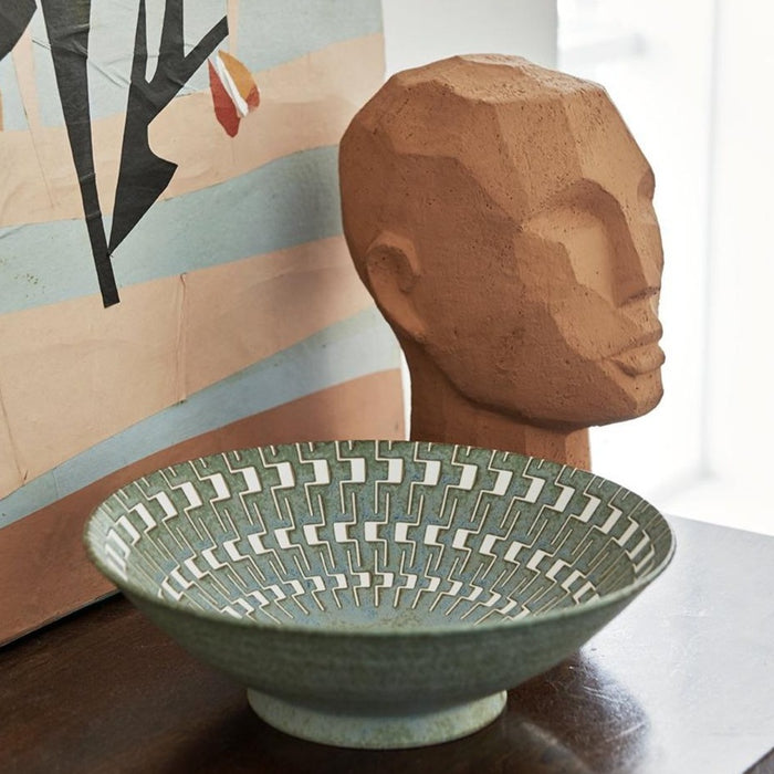 abstract head sculpture in terracotta next to a bowl
