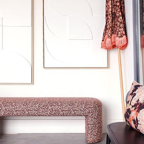 upholstered bench with a brown flower vintage inspired fabric and a beach umbrella with orange fringes