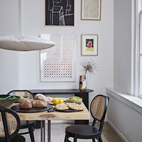 dining room with black and webbing chairs, a gallery wall with art and a white ufo shaped ceiling light