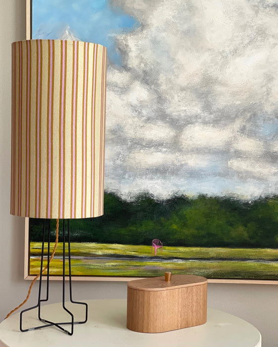 pink, yellow and brown striped table lamp on an open base with a golden electrical cord