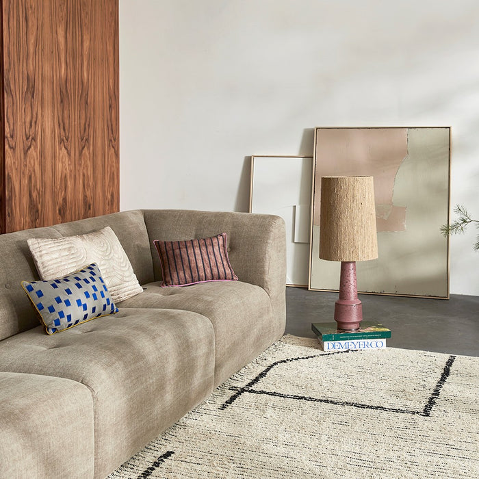 mid century modern style living room area with linen blend element  sofa natural cotton area rug and retro inpired table lamp with purple base and brown shade
