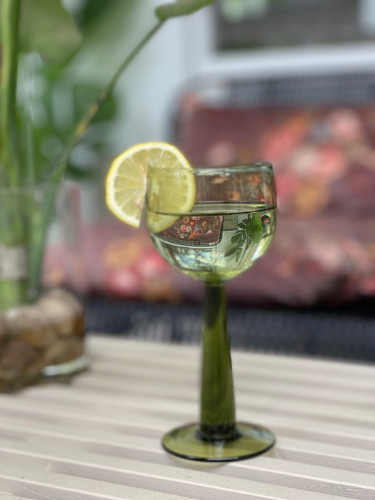 green wineglass with tall stem filled with water and a slice of lemon