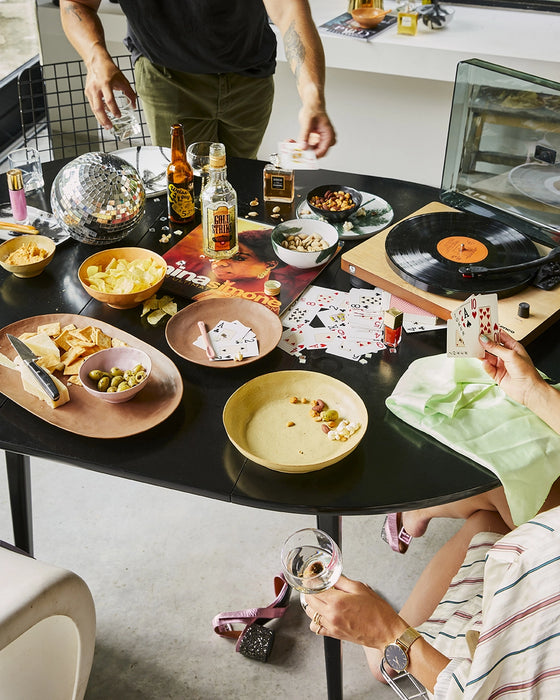 table filled with snacks, cards, a record player and an oval shaped serving platter