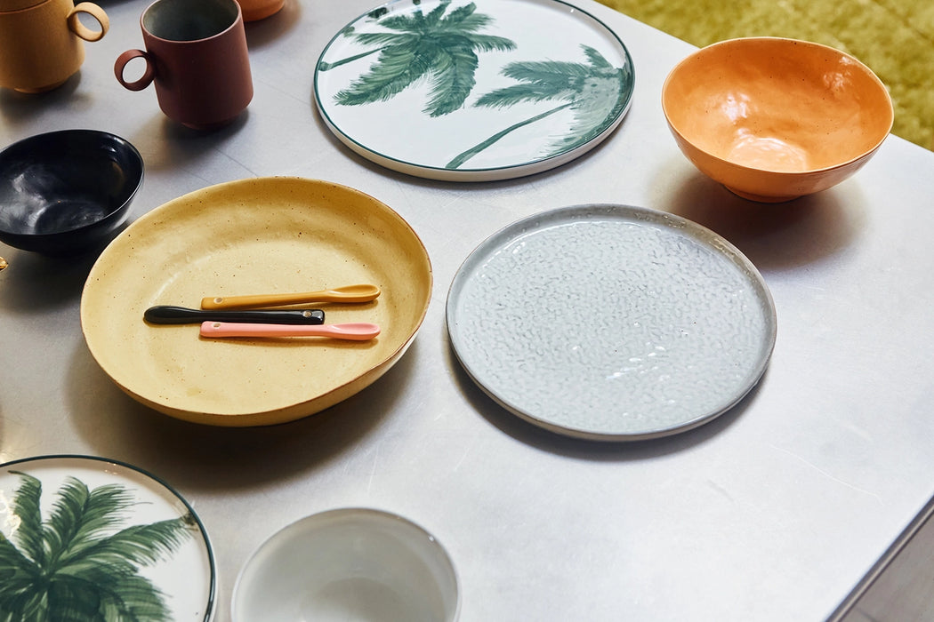 yellow plate, white plate and palm tree plate and an orange bowl on a table