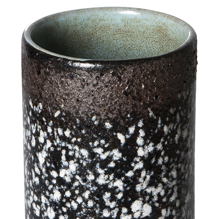 detail of brown, black and white flower vase with green inside
