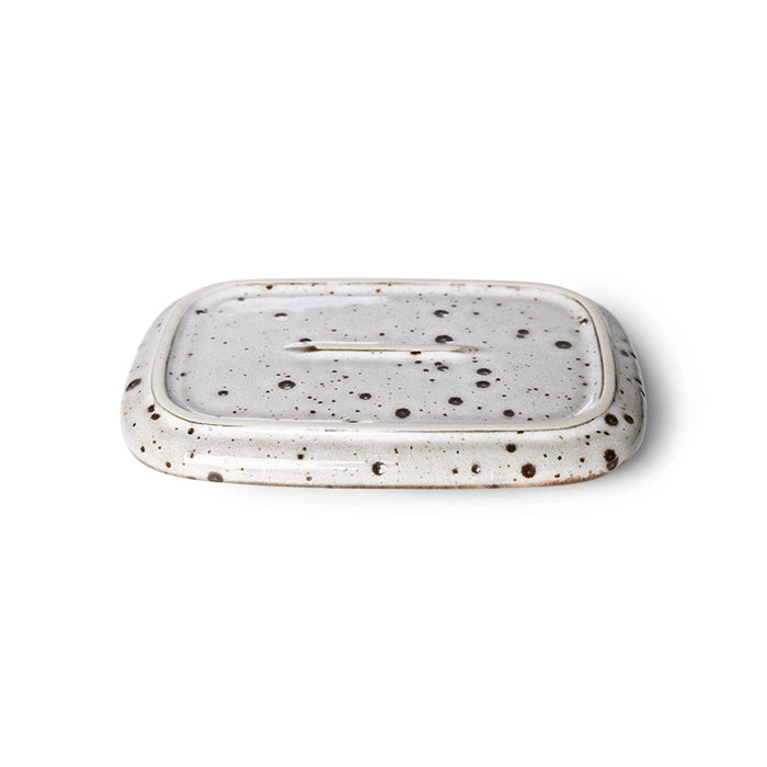 bottom of a small, stoneware tray in cream white with dark grey speckles