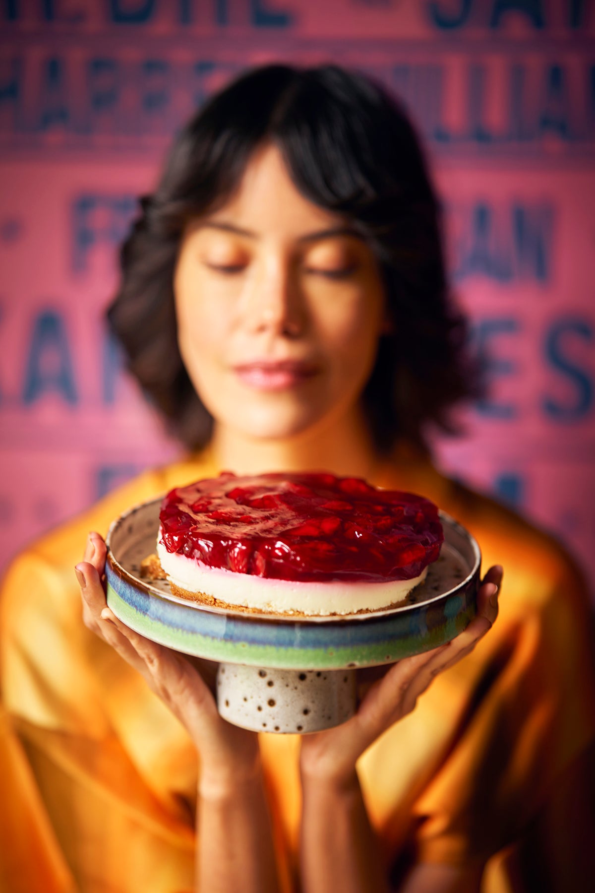 woamn holding retro style cake stand with cheesecake