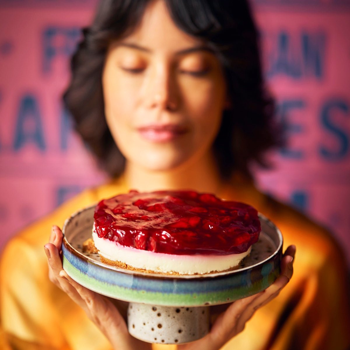 woamn holding retro style cake stand with cheesecake