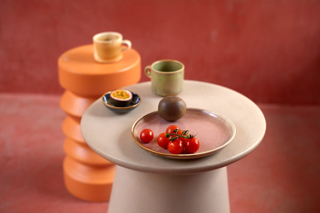 pink side plate on a beige side table with red tomato's and dragon fruit 