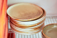 close up photo of a stack hotel porcelain cream and brown dinnerplates