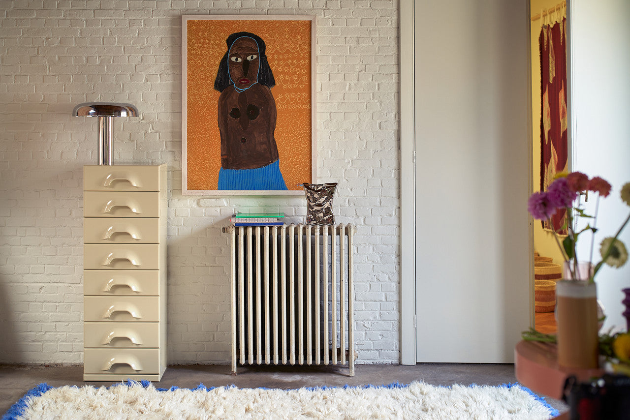 bag of chips silver vase object on a radiator in a living room with a large modern painting