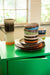 4 stoneware dessert bowls with groovy colors stacked up on a green cabinet