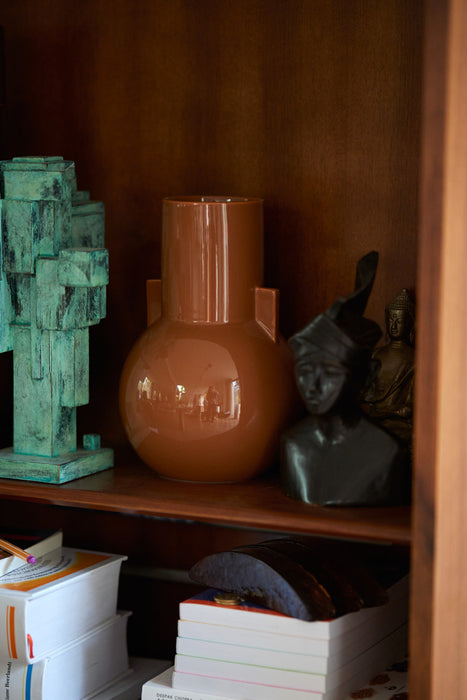 small elegant caramel brown flower vase in open shelving with a small sculpture next to it