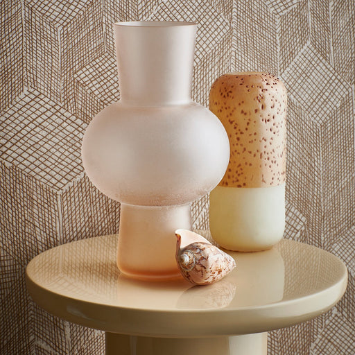 sand blasted glass flower vase in peach color on a shiny cream colored table