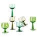 high and low stemmed green colored wine glasses