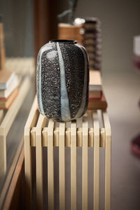 monochrome glass vase on a sand colored slatted bench