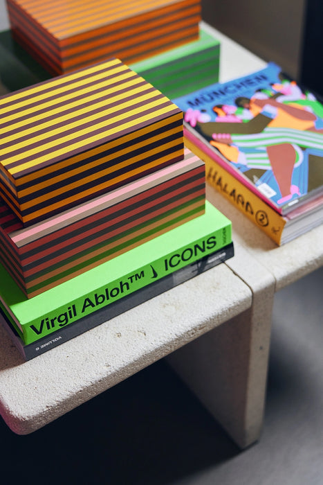 handmade striped boxes on a side table filled with bright colored books