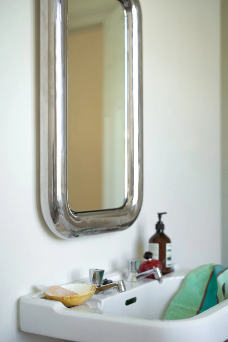 rectangular chrome chubby mirror hanging above small white sink