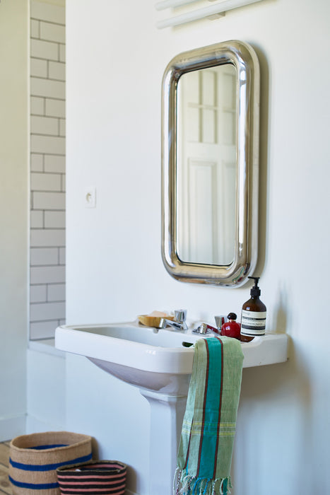 rectangular chrome chubby mirror in bathroom with blue green towel