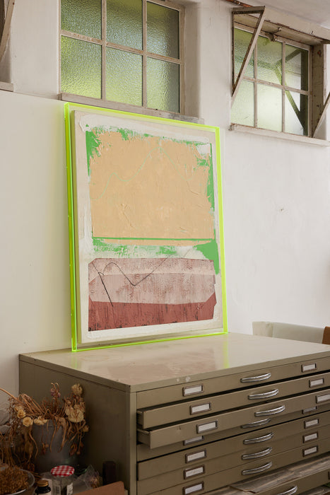large abstract painting with neon yellow frame on a drawer in industrial space