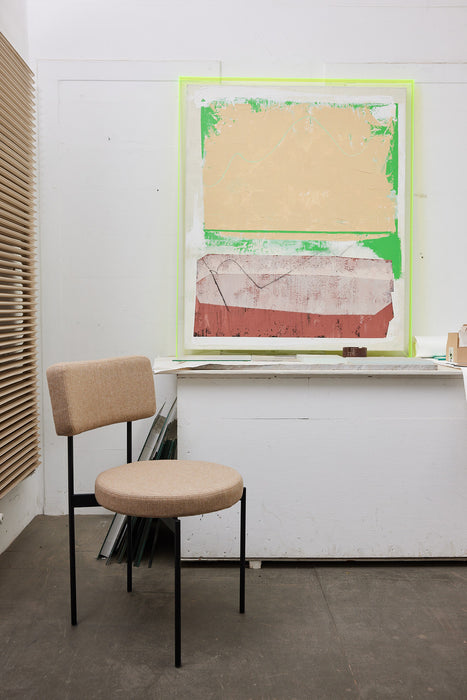 large abstract painting with neon yellow frame in an office with a chair