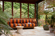 sculpture like earthenware accent table in front of orange and brown striped outdoor sofa