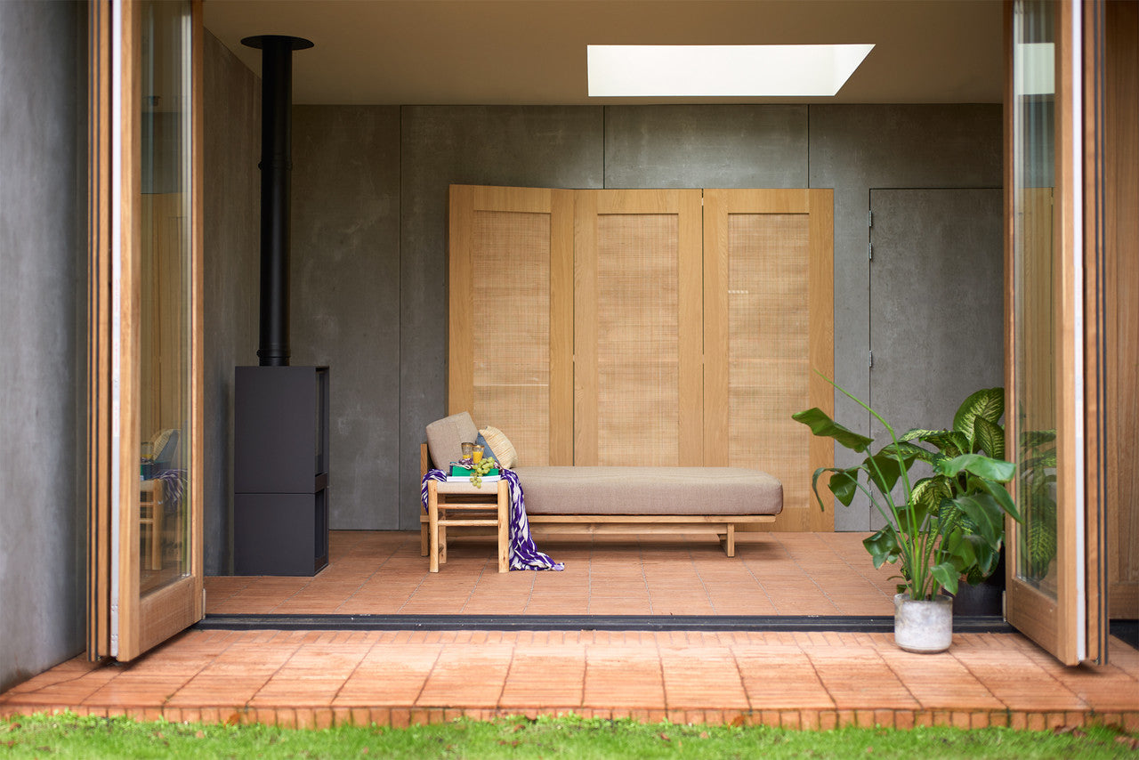 teak wooden day bed with beige cushion in a sun room
