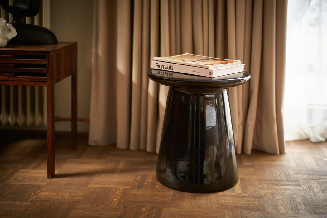 glossy finish black earthenware accent table with books on top