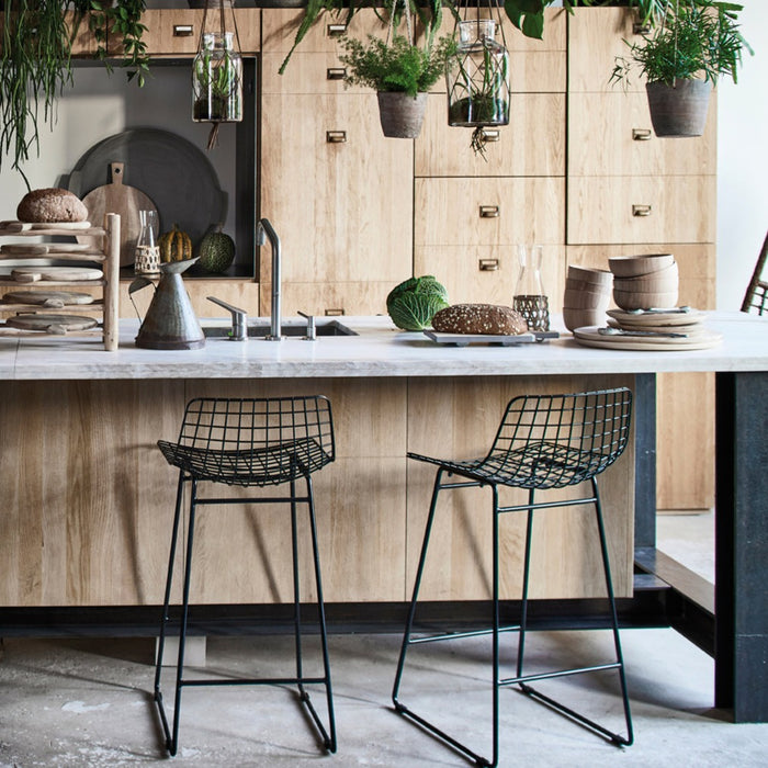 natural wooden kitchen with black metal counter stools and lots of hanging plants
