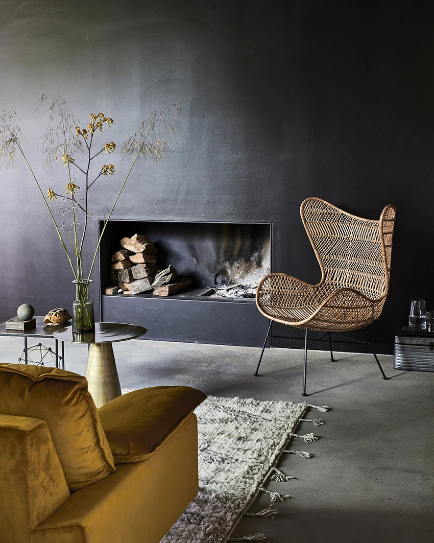 retro style 2 seater small sofa with ochre yellow velvet fabric and detachable cushions in a sophisticated chic interior with a black wall and a fire place