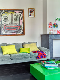 velvet mint green sofa with yellow pillows and a green coffee table with photobooks