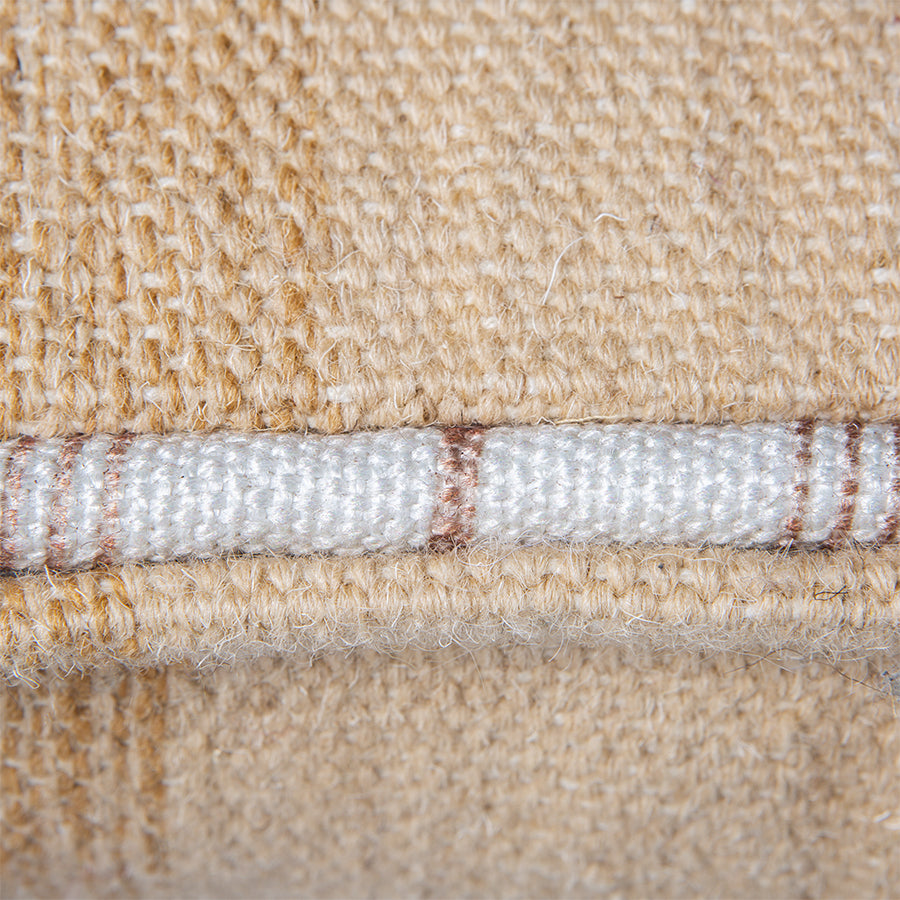 detail of large handwoven woolen lumbar pillow in neutrals with white piping