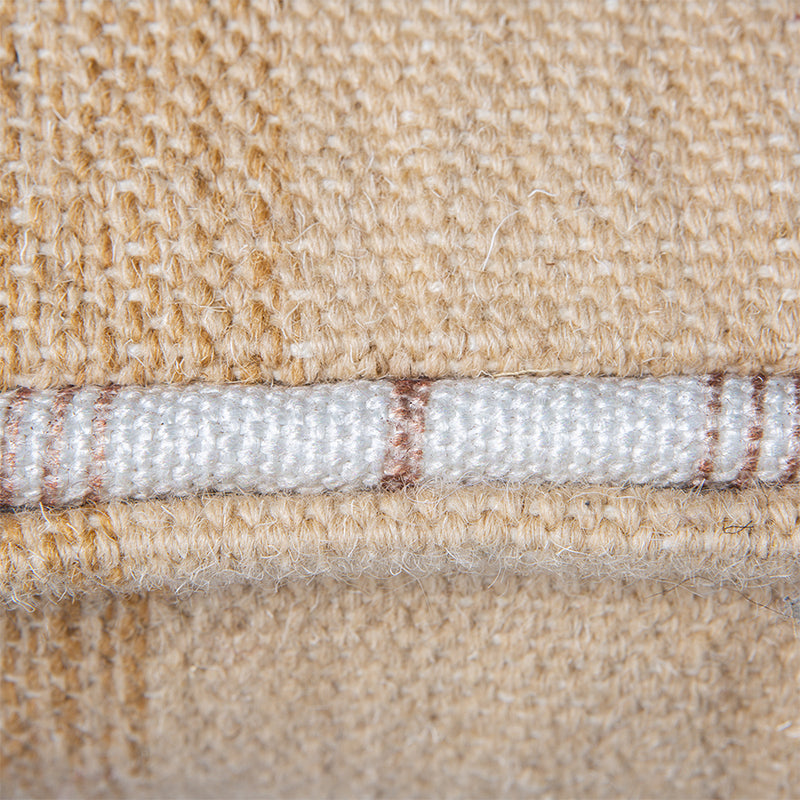 detail of large handwoven woolen lumbar pillow in neutrals with white piping