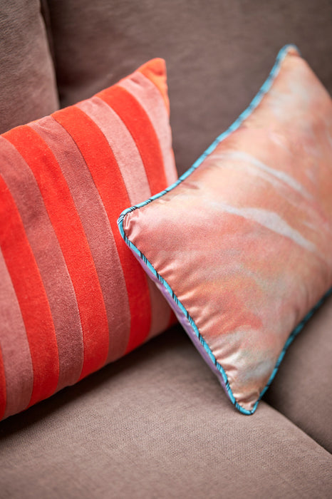velvet accent pillow with two shades of red stripes next to a silk pillow with turquoise trim