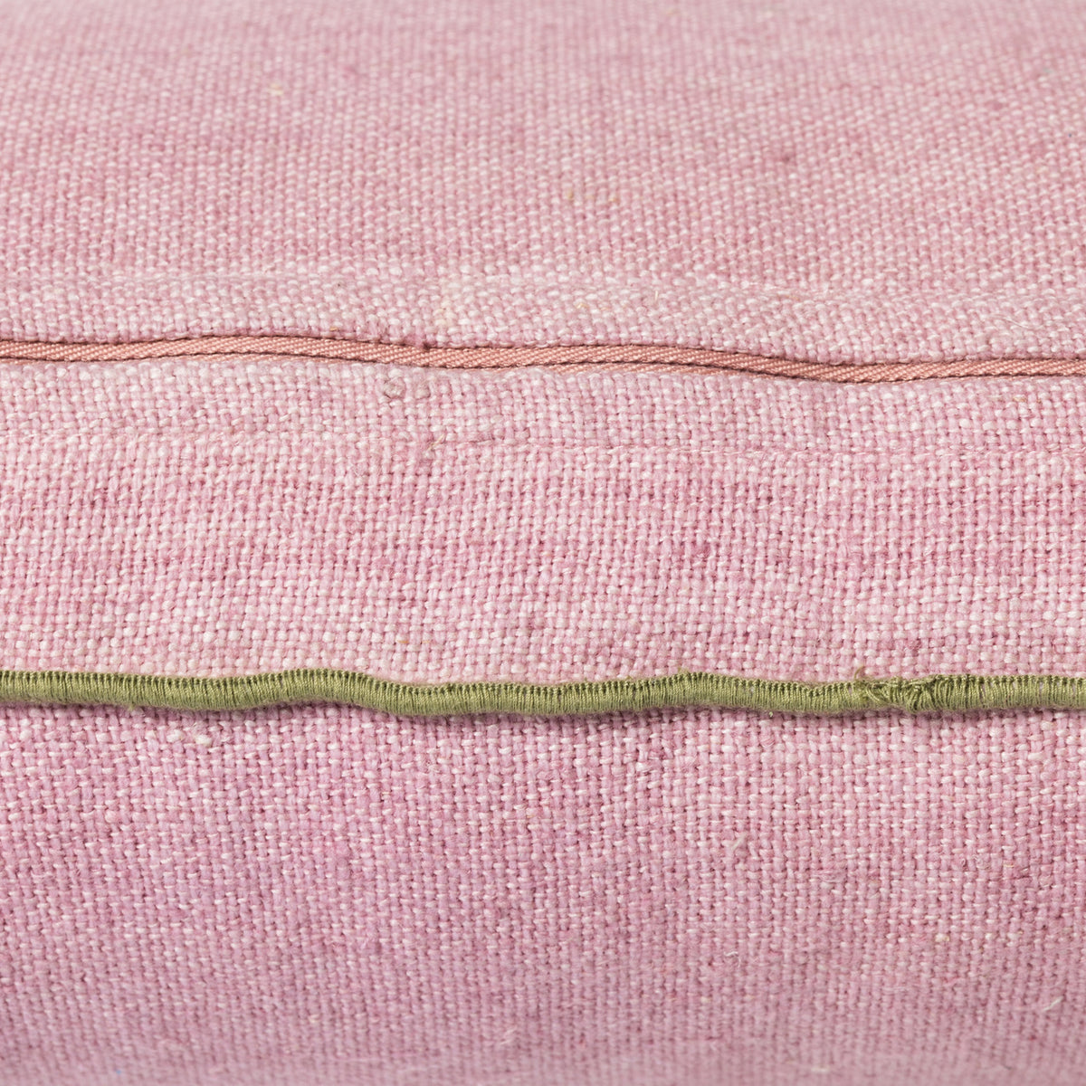 detail of pink linen lumbar shaped pillow with green cotton trim