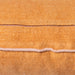 detail of lumbar shape orange linen pillow with a blush colored cotton trim