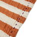 detail of tangerine and white striped napkin with purple stitches