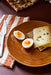 tangerine and white striped napkin next to a brown plate with an egg and a slice of bread with cheese