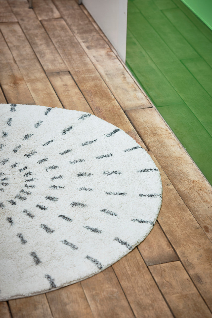 round white bathroom rug with hand silkscreened charcoal stripes next to a green bath