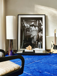 brown stoneware floor lamp with white shade and large black and white photo and blue area rug