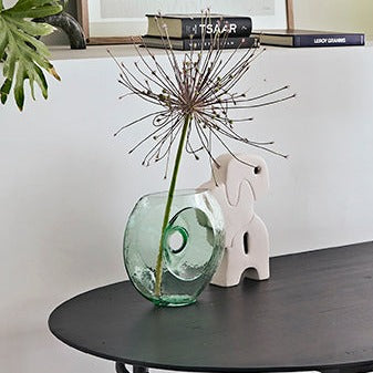 glass flower vase with single flower and a white sculpture on a black table