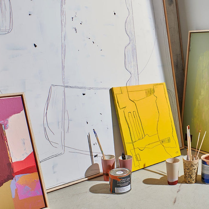 abstract paintings in white, yellow and purple on floor in artist studio