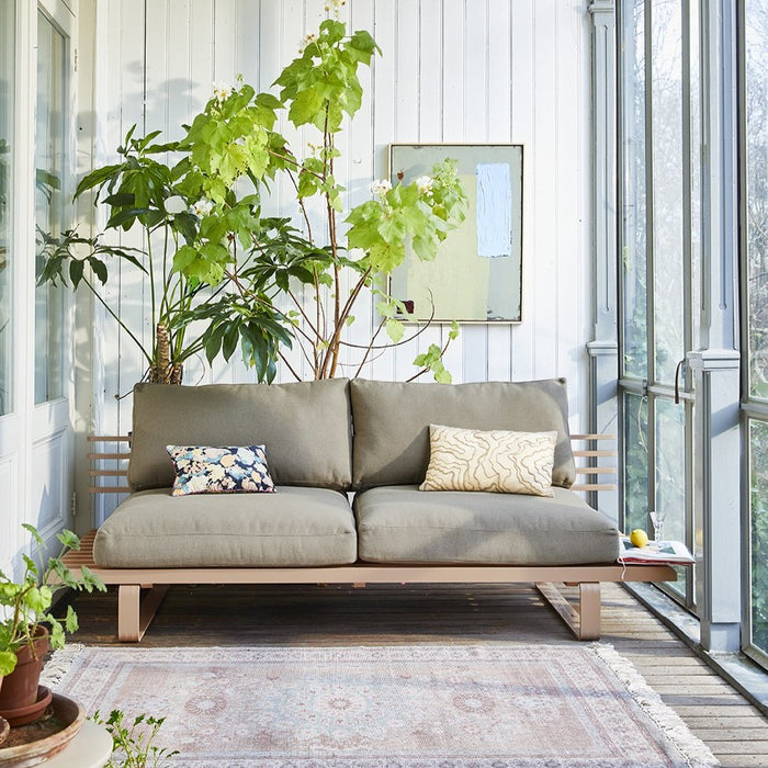 sun room with outdoor bench with cushions and an abstract painting on the wall