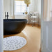 bathroom with black and white round rug in front of black bath tub